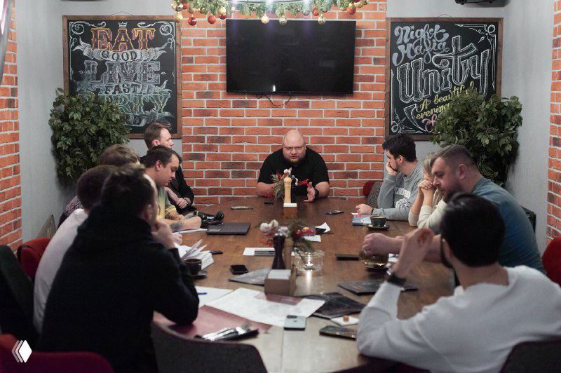 Кадр с круглым столом во время живого разбора: участники слушают ведущего, заметна концентрация и серьёзное отношение к обсуждаемым внутренним темам.