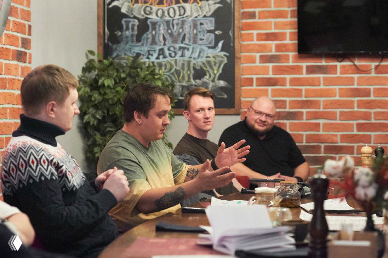 Несколько участников активно жестикулируют и обсуждают услышанное, видно эмоциональное вовлечение и обмен мнениями в тренинговой сессии.