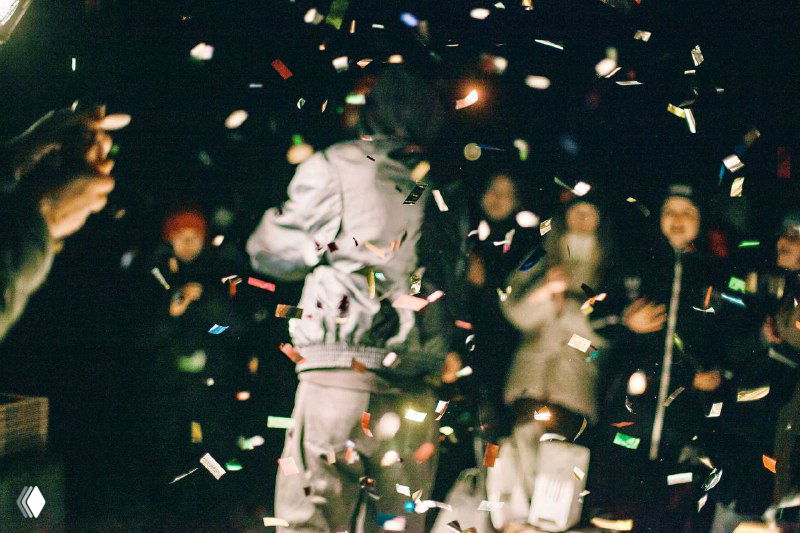 Праздничная сцена с конфетти в воздухе и силуэтами людей: динамичное фото праздника, эмоции и коллективные события.