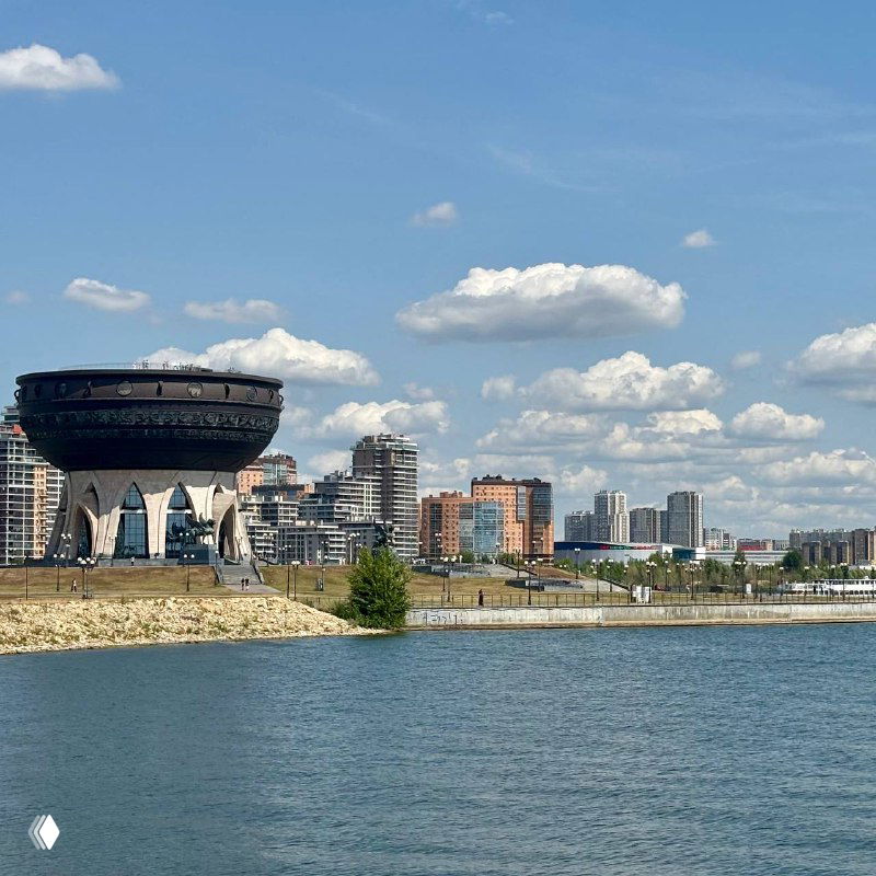 Вид через реку на чашеобразный Центр семьи «Казан» и городской горизонт с жилыми домами и ясным небом, панорамный кадр набережной.