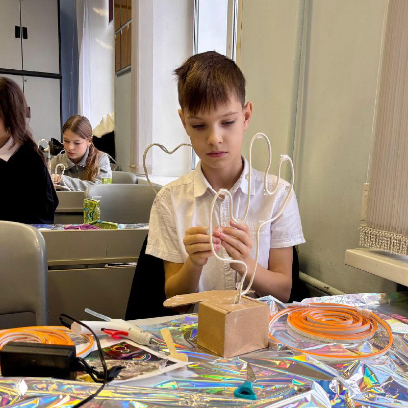 Ученик за рабочим столом мастерит научный или творческий проект в кабинете — занятие по технике или рукоделию, развитие практических навыков в школе.