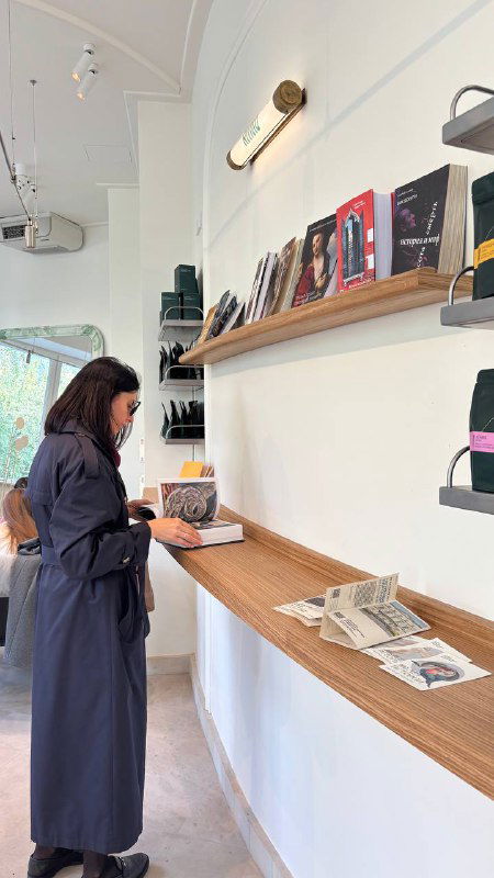 Девушка у длинной барной стойки с книгами и ноутбуком: рабочая и спокойная обеденная зона для встреч и чтения, светлый интерьер и стойка у окна.