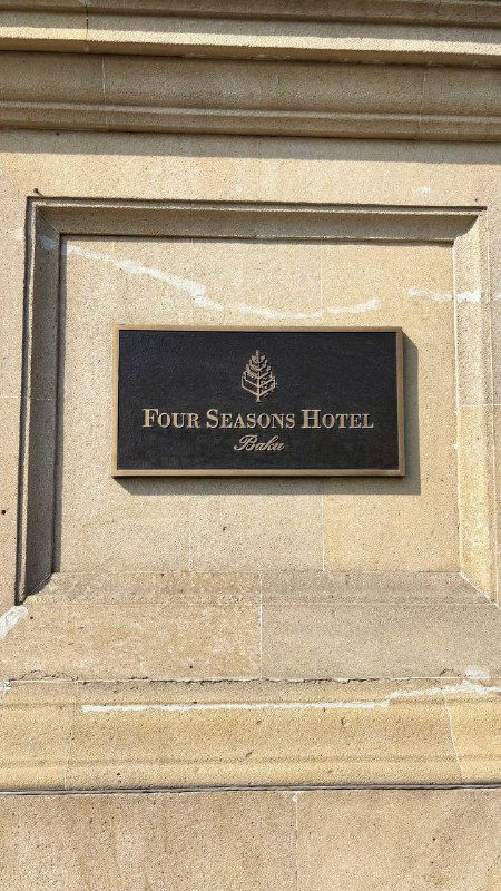 Табличка отеля Four Seasons Baku на каменной стене, крупный план вывески, лаконичная идентификация места проживания и гостиничная эстетика