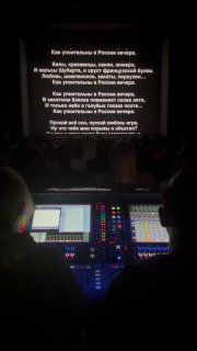 Рабочая панель звукорежиссуры и фрагмент проекции текста на сцене, вид с технического пульта внизу зала