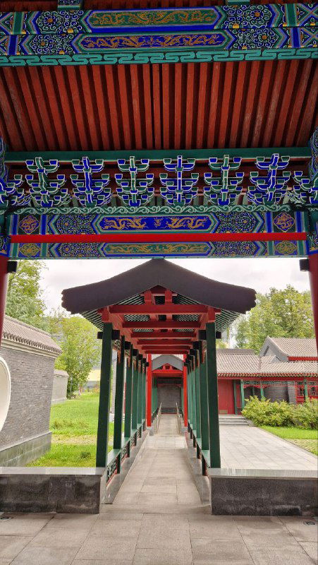 Красочный крытый коридор с традиционной росписью и колоннами, приведший к внутренним дворикам китайского парка в Москве.
