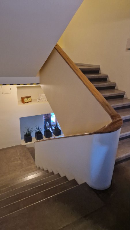 Внутренняя лестница Дома Наркомфина: простые перила, широкие ступени и открытое пространство лестничного холла, сохранившее исторический характер.