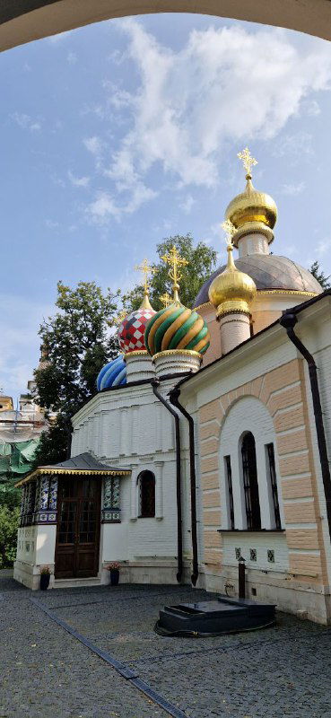 Боковой фасад и несколько куполов Спасо‑Преображенской церкви в Переделкине на фоне неба; вид с прогулочной аллеи рядом с храмом.