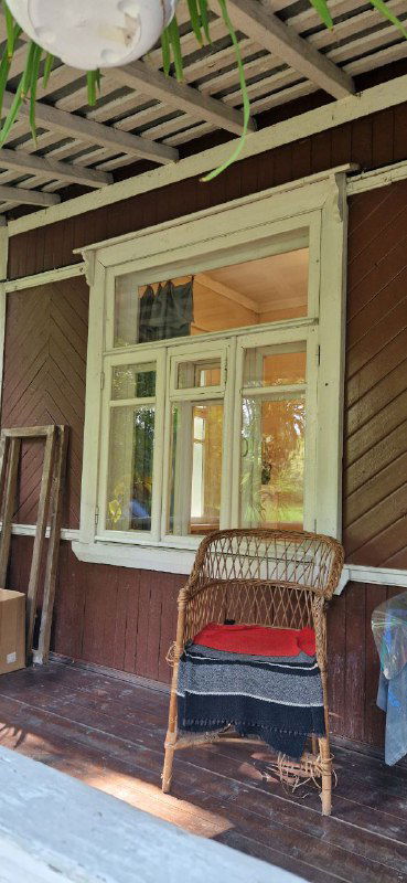 Веранда или крыльцо деревянного дома-музея Пастернака: плетёное кресло, окно и элементы наружного убранства усадьбы в Переделкине.