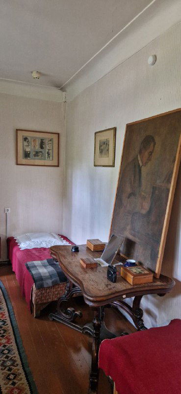 Рабочая комната с двумя кроватями и столом, на котором лежат книги и предметы быта — экспозиция, передающая повседневность писателя.