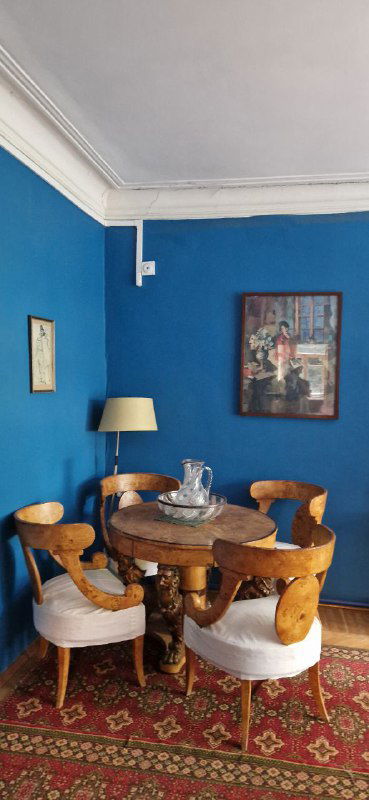 Интерьер дома-музея: уютная синяя комната с круглым столом, креслами и картиной на стене — ощущение жилого пространства писателя.