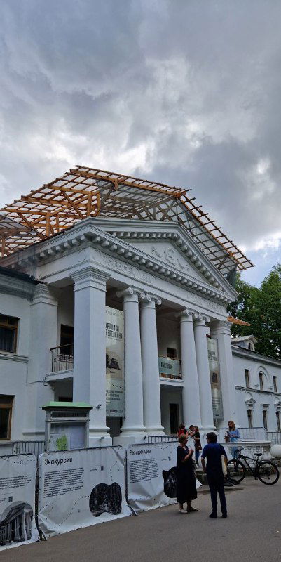 Фасад дома творчества писателей в Переделкино под строительными лесами, на фоне пасмурного неба и людей у входа — временные ограждения видны.