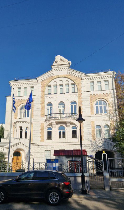 Величественный фасад особняка в стиле модерн (возможно Морозова): арочные окна, декоративные элементы и флаги у парадного входа на городской улице.