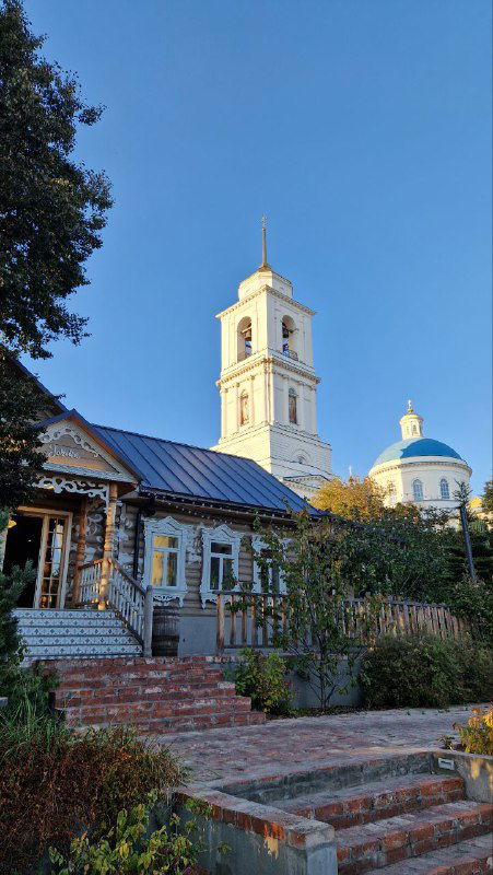 Колокольня и купол старообрядческой церкви в Серпухове: белые фасады, деревянное крыльцо и ясное небо в тихий осенний день.