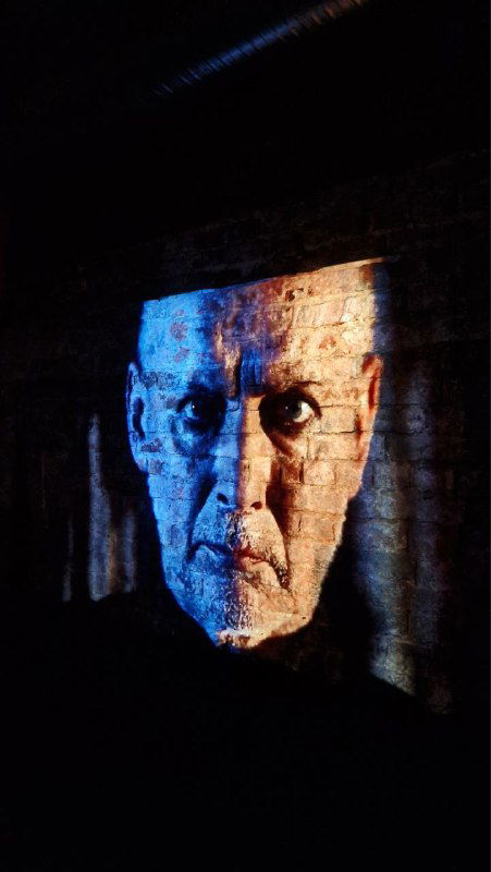 Крупная проекция лица Клавдия на экран — эффект «всевидящего ока», используемый в постановке для усиления образа и власти персонажа на сцене.