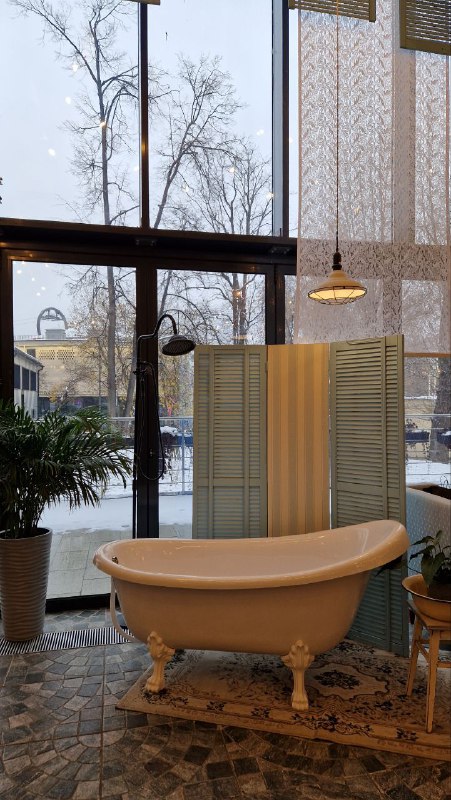 Свободно стоящая винтажная ванна у панорамного окна кафе, за окном виднеется зимний городской пейзаж — ещё одна нестандартная фотозона.