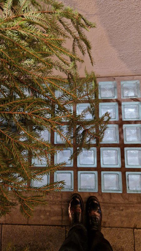 Фрагмент пола из стеклоблоков и низкий ракурс: вид на стеклоблоки, часть фасада и туфли автора — акцент на сохранившиеся материалы и детали.