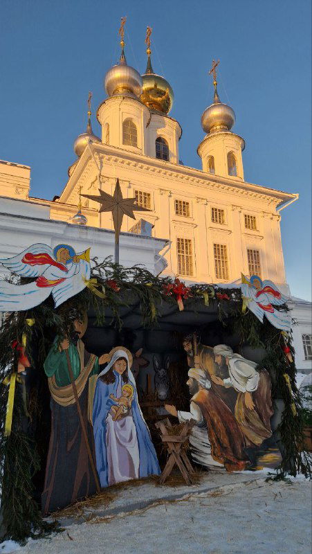 Вертеп перед фасадом Никольского собора: фигурки Рождества, праздничная декорация на фоне старинного храма в тёплом свете заката.