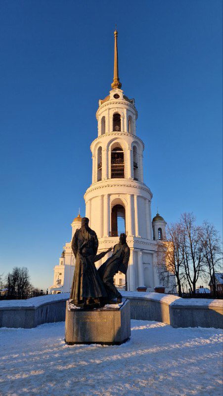 Колокольня и памятник новомученникам на заснеженном постаменте при золотом свете закатного неба в историческом центре Шуи.