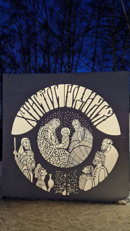 Световая панель с христианской иллюстрацией из парка «Путь света»: белые контуры сюжетов на тёмном фоне в вечерней подсветке.