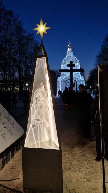 Пирамидальная световая инсталляция и силуэт храма с крестом на фоне — композиция ночного паркового оформления фестиваля.