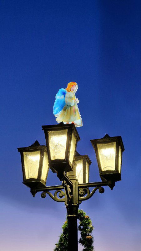 Небольшая декоративная фигурка ангела на фонарном столбе против глубокого синего неба — уличная рождественская деталь в Шуе.
