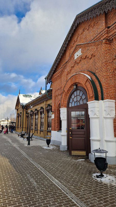 Боковой вид здания вокзала Шуи: протяжённый кирпичный ряд с арочными окнами и заснеженной пешеходной плиткой вдоль фасада.