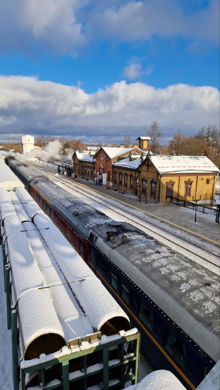 Вид сверху на шуйский вокзал и подходящий поезд: крыши зданий под снегом, платформа и композиция поезда из ретро-вагонов.