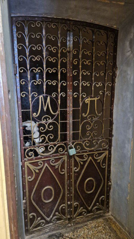 Кованая дверь с декоративной решёткой и инициалами «МП», вид на входную створку усадьбы М.А. Павлова; старинная металлоконструкция и замок.