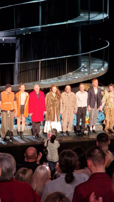 Актёрский поклон после спектакля: вся труппа на переднем плане, позади видно конструкцию спиральной лестницы — центральная декорация постановки.