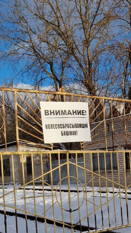 Забор с предупреждающей табличкой на фоне снега и деревьев в Шуе — бытовая деталь городского пространства зимой.