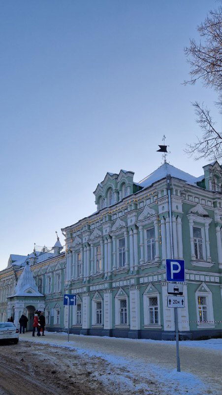 Парадный исторический дом с богатым декором и колоннами, заснеженные тротуары и редкие прохожие в центре Шуи.