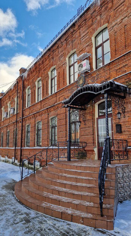 Краснокирпичное здание с входной лестницей и заснеженным тротуаром — пример исторической застройки Шуи и местных музеев.