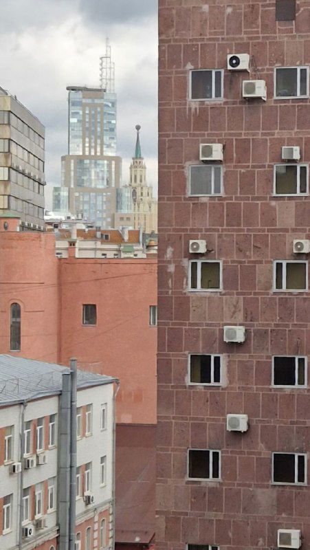 Вид через окна на соседние фасады и высотные постройки за зданием Центросоюза: урбанистический пейзаж с кондиционерами и окнами.
