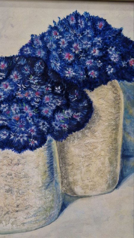 Крупный план вышивки с синими цветами из выставки «Дыхание природы. Магия цветов», заметна текстура ткани и детальная проработка стежков.