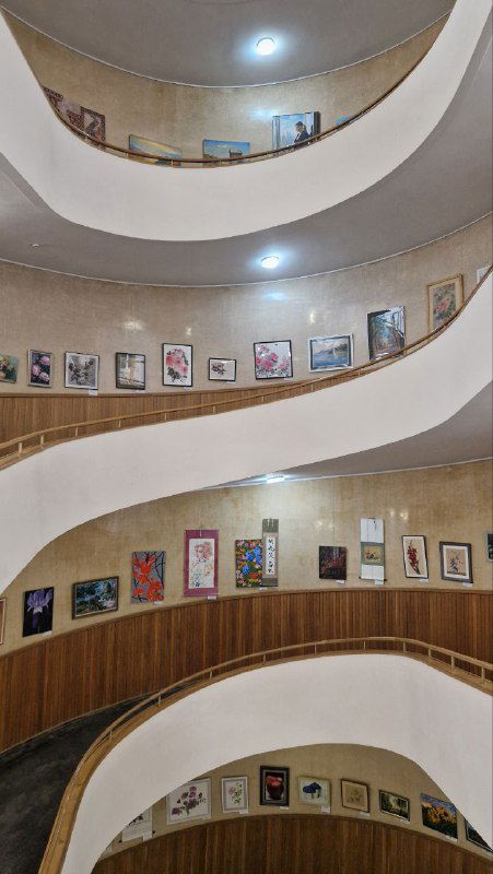 Изогнутые балконы и галереи внутри выставочного зала Центросоюза — архитектурный ракурс с развешенными экспонатами по периметру.