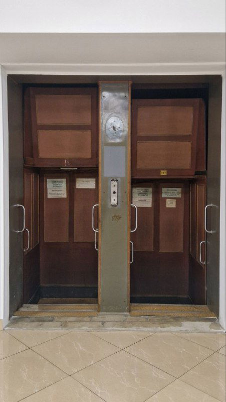 Патерностер — ряд маленьких кабинок лифта непрерывного действия, теперь музейный экспонат, рядом виден обычный лифт и двери шахты.