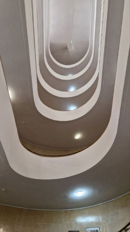 Взгляд вверх по вертикальной шахте с овальными проёмами и вмонтированными светильниками — дизайнерский приём в интерьере Центросоюза.