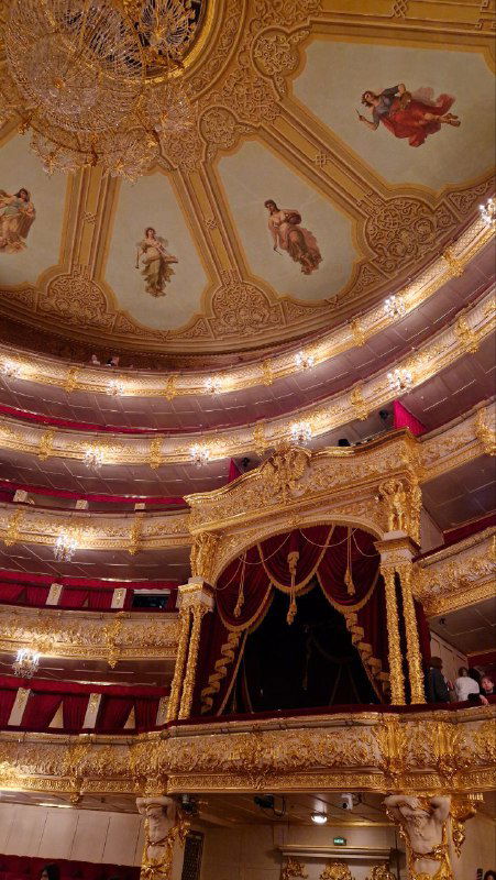 Вид зрительного зала Большого театра с куполом и фресками на потолке, многоярусными ложами и богато украшенной сценой.
