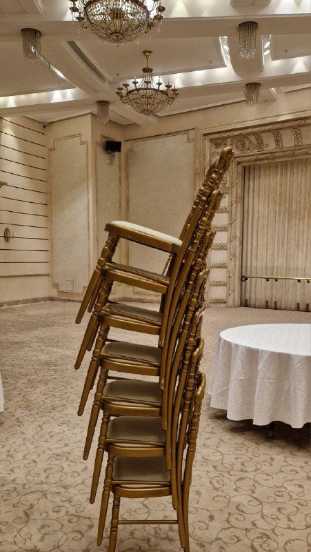 Боковой зал или банкетное помещение Большого театра с люстрами и стопкой деревянных стульев — вид служебной или вспомогательной зоны.