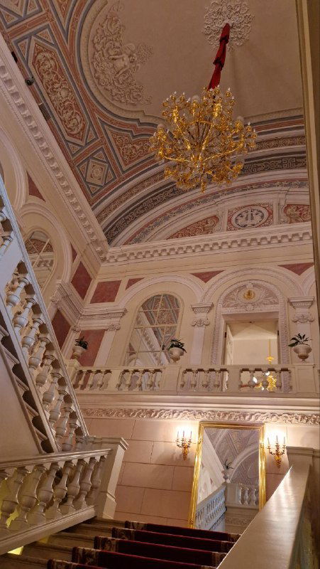 Интерьер фойе Большого театра: потолки с росписями, лепнина и балюстрады в пастельных тонах, вид на архитектурные детали и освещение.