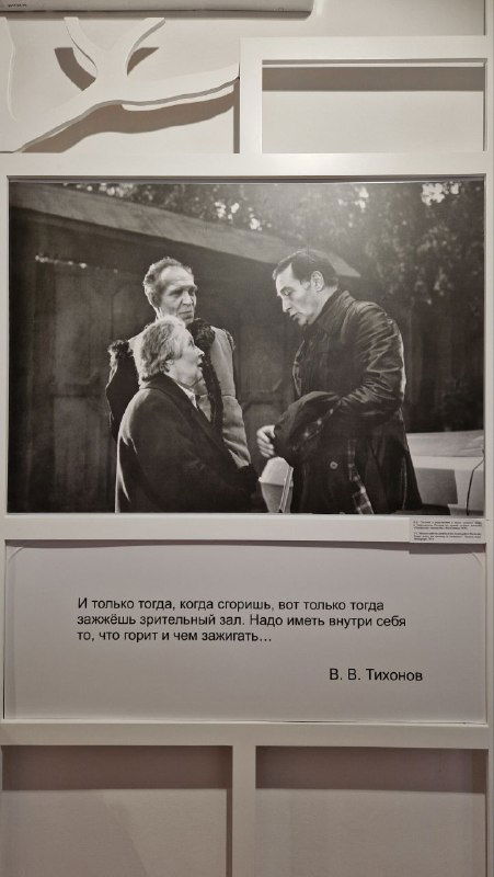Чёрно‑белая фотография из фильма на стене музея с подписью‑цитатой В. Тихонова под изображением — драматический кадр экспозиции.