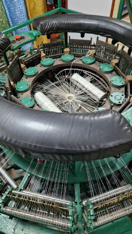 Круговой вид ткацкого механизма в музее: станок с катушками и нитями, демонстрация технологической части текстильного производства.