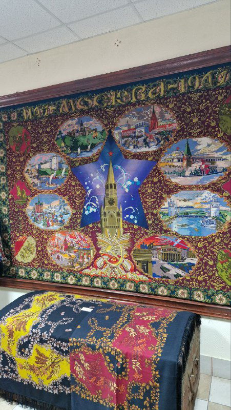 Большой декоративный павлопосадский платок на стене музея: яркий узор, сцены и элементы местной истории, оформленный как центральный экспонат.