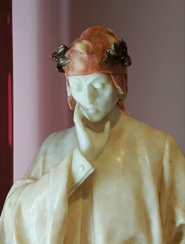 Мраморная или каменная скульптура головы на розовом фоне экспозиционной витрины — часть собрания скульптуры музея.