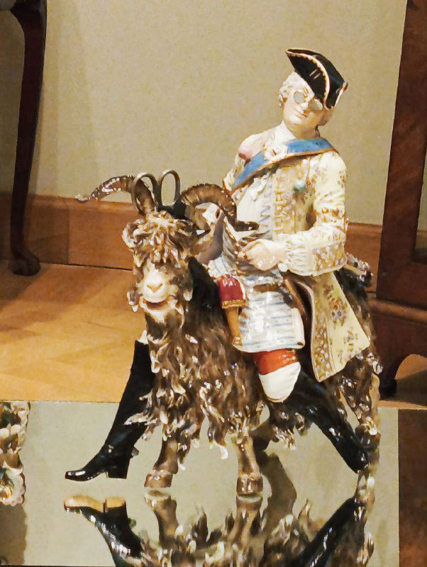Фарфоровая фигурка всадника или декоративная миниатюра на стеклянной поверхности витрины — часть декоративно-прикладного собрания.