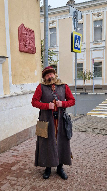 Человек в историческом костюме стоит у старого дома в Твери — атмосферный уличный персонаж для прогулок и фотографий в центре