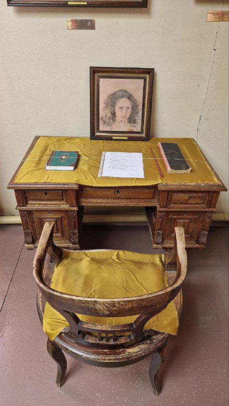 Письменный стол и кресло с жёлтой обивкой в музее Домотканово, на столе лежат документы и книги — музейная инсталляция личного кабинета.
