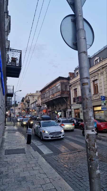 Улица Тбилиси с оживлённым движением: автомобили в ряд, узкая тротуарная зона и городской стритсоут — типичная центральная магистраль.