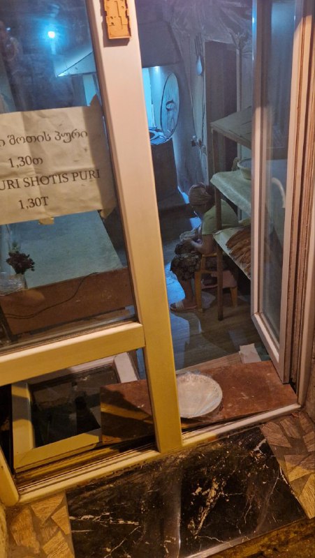 Витрина с местной пекарней и шоти‑пури на подносе в дверном проёме — традиционный грузинский хлеб, готовящийся прямо у улицы.