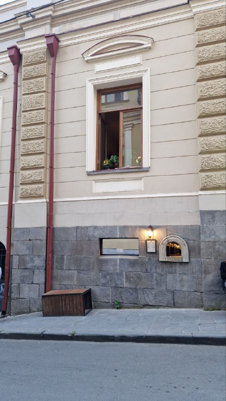 Невыразный фасад старого дома в Тбилиси с окном и почтовым ящиком у тротуара — городской уличный фрагмент исторического района.